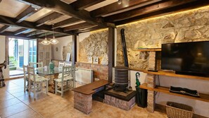 A cozy living area with a stone wall, a fireplace, a television, and a dining table with chairs.