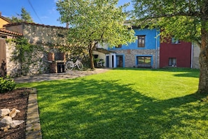 A courtyard with a bicycle, stone walls, and a grassy lawn.