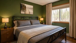 Un dormitorio con una cama, dos mesitas de noche con lámparas, una ventana con cortinas y un cuadro en la pared.