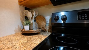 Una cocina con encimeras de granito, horno de acero inoxidable y tabla de madera con utensilios.