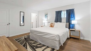 A bedroom with a bed, bedside tables, a mirror, and a window with curtains. - Mins to Downtown! Chic & Modern - Elegant in Noir (Chattanooga)