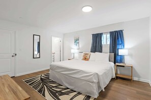 Ein Schlafzimmer mit Bett, Nachttischen, einem Spiegel und einem Fenster mit Vorhängen.