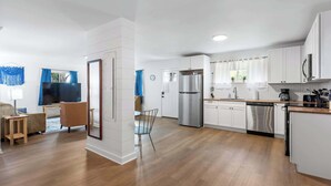 A modern kitchen with white cabinets, stainless steel appliances, and a wooden floor. - Mins to Downtown! Chic & Modern - Elegant in Noir (Chattanooga)