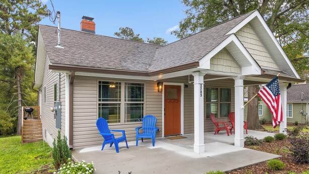Ein Haus mit einer Veranda, zwei blauen Stühlen, einer US-amerikanischen Flagge und der Hausnummer 3705 an der Tür.