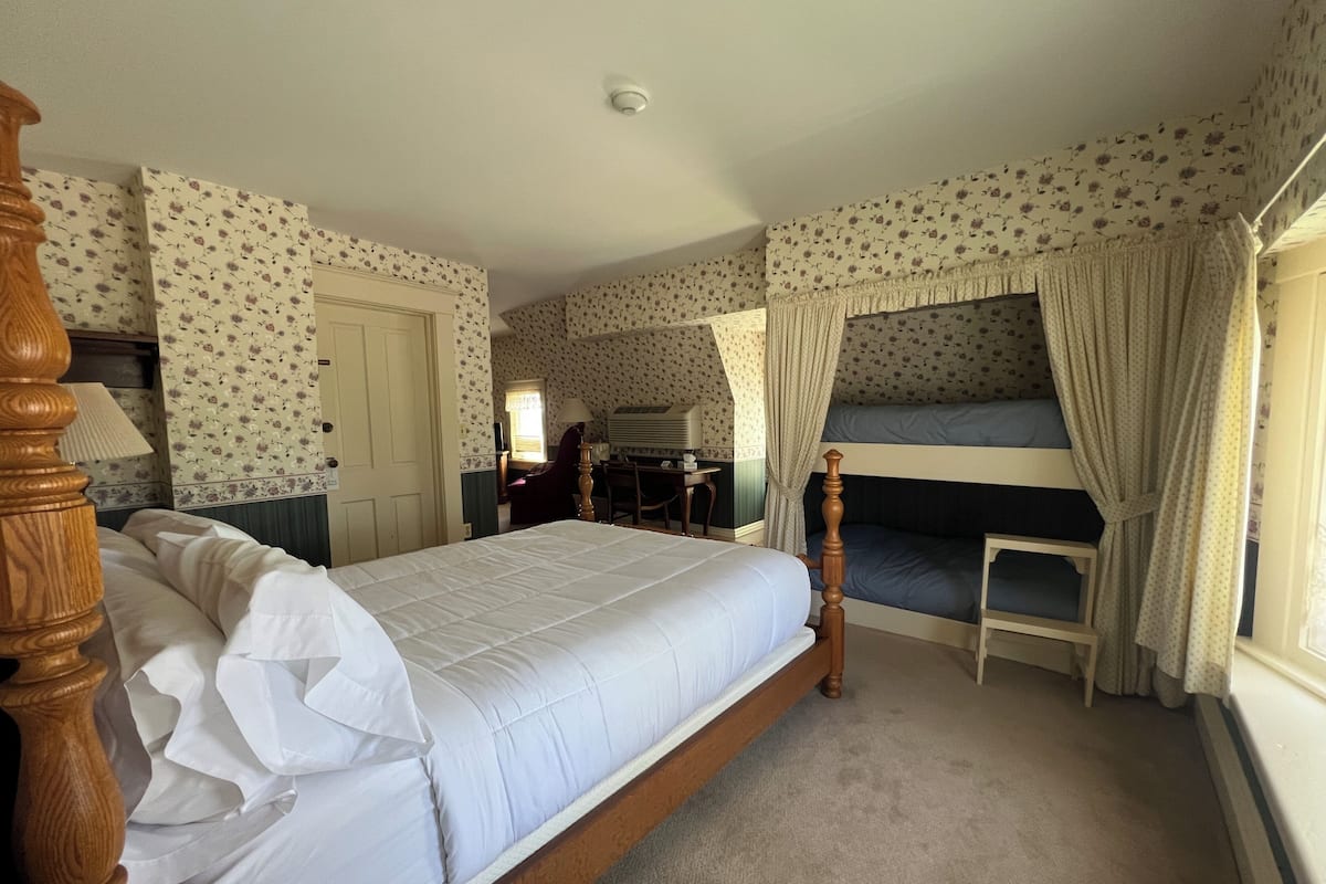 A bedroom with a single bed, a bunk bed, a desk, and a chair.