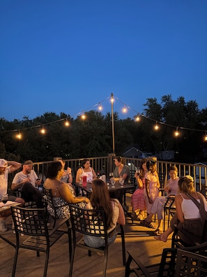 An outdoor seating area with tables and chairs, surrounded by trees and string lights. - Strawtown Inn & Events (Pella)