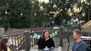 Une terrasse extérieure avec une table, des chaises et une banderole d’anniversaire.