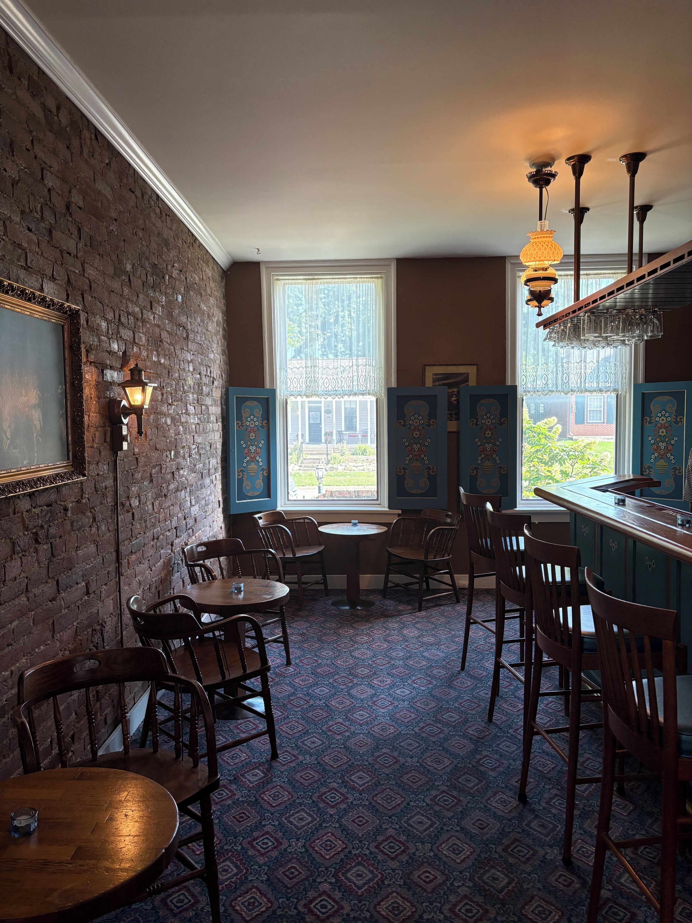 A room with brick walls, a patterned carpet, and a bar area with stools.
