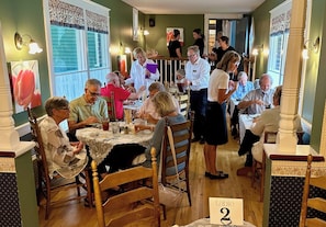 A dining area with wooden tables, chairs, and a variety of people engaged in conversation and dining.
