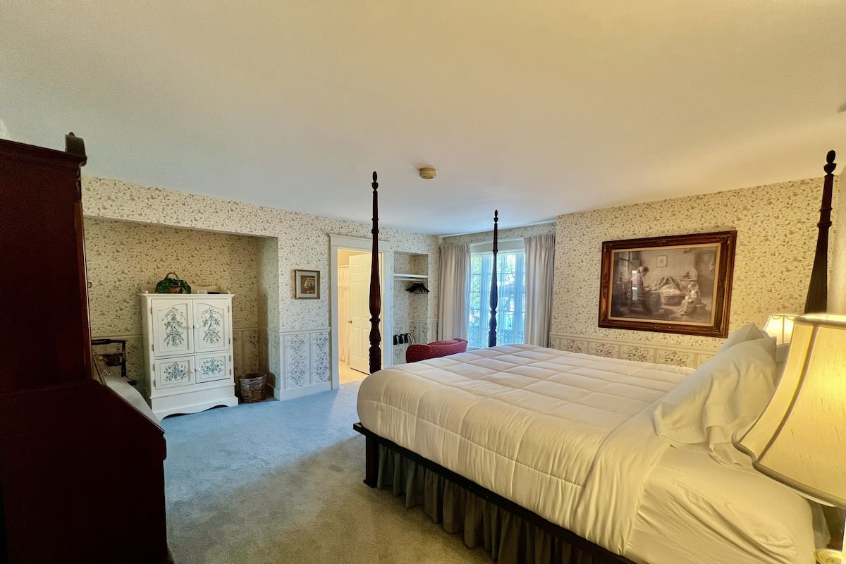 A bedroom with a four-poster bed, a dresser, and a painting on the wall.