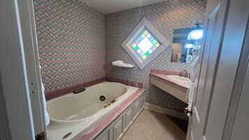 Ein Badezimmer mit freistehender Badewanne, einem Waschtisch und einem Spiegel.
