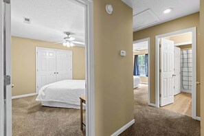 Une chambre à coucher avec un lit, un ventilateur de plafond et une porte donnant sur une autre pièce.