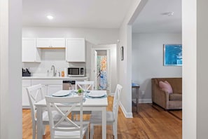A modern kitchen with white cabinets, a dining table with chairs, a microwave, and a painting on the wall. - Minutes to the Zoo & Downtown! - McCallie Dugout (Chattanooga)