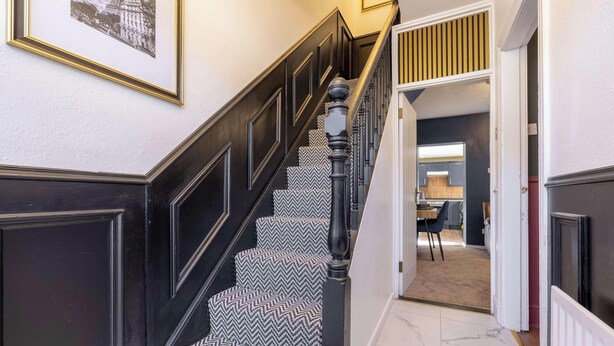 A staircase with patterned carpet, dark wood railings, and a framed picture on the wall.