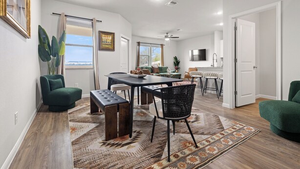 A dining area with a table, chairs, and a bench, a kitchen area with a sink and cabinets, and a large window with curtains. - Modern Farmhouse Retreat w Patio & Yard (Lockhart)