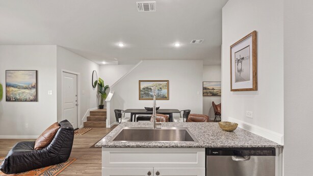 A modern kitchen with a granite countertop, stainless steel sink, and dishwasher.