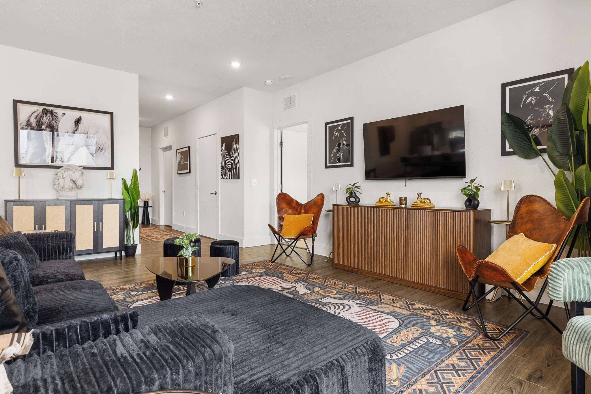 A modern living room with a sofa, chairs, a coffee table, a TV, and artwork on the walls.