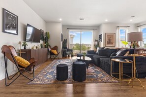 Een woonkamer met een bank, salontafel en televisie. Er is een balkon met uitzicht.