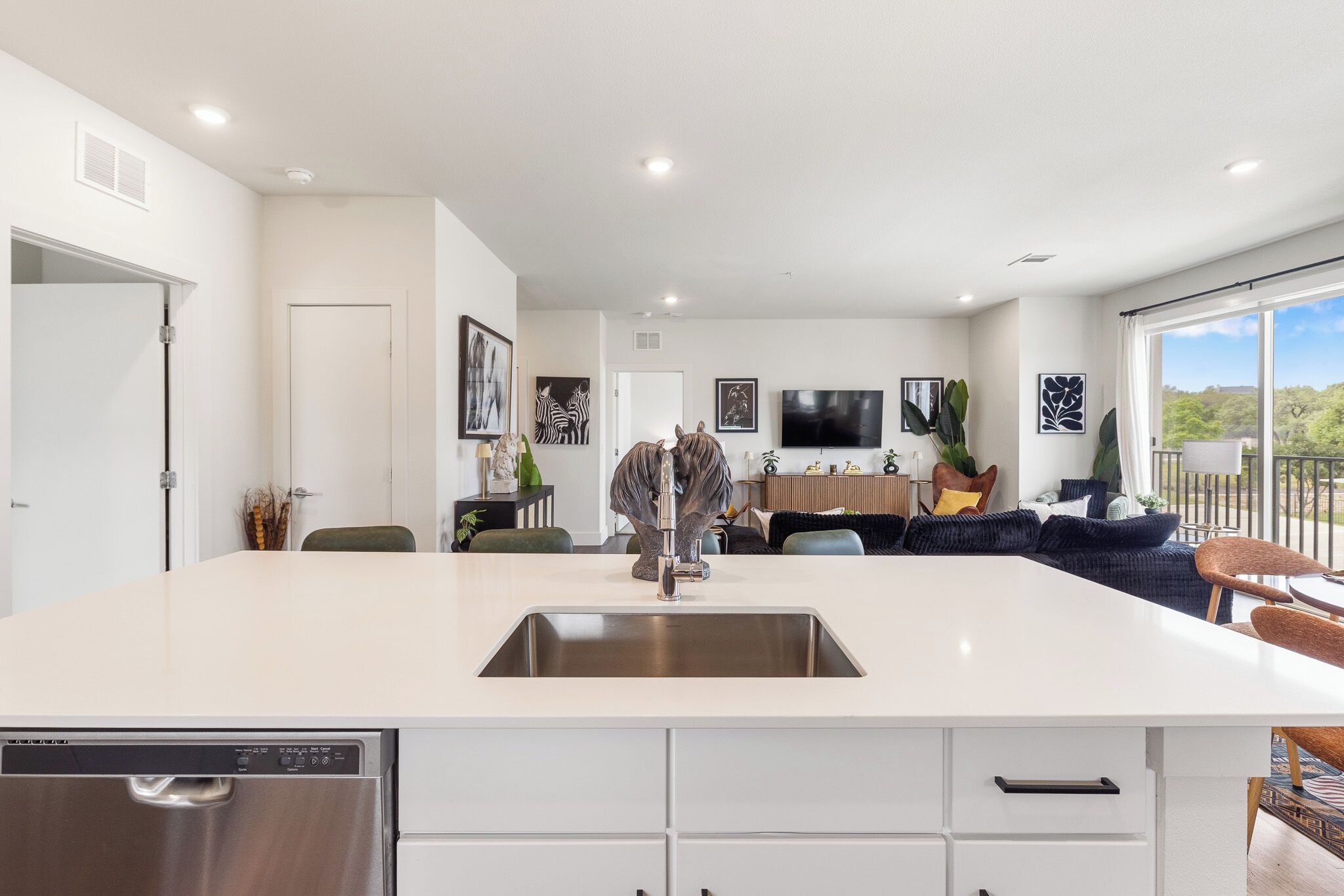 A modern kitchen with a central island, a built-in dishwasher, and a dining area with a view.
