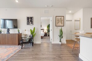 Ein modernes Wohnzimmer mit Fernseher, Kunstwerken und einem Holztresen.