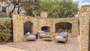Un patio de piedra con mobiliario exterior, una chimenea y un muro de piedra.