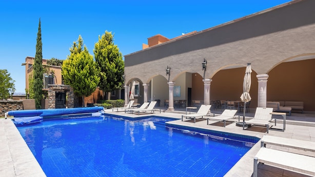 Ein Swimmingpool mit Liegestühlen und einer überdachten Terrasse.