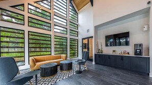 A modern interior with a sofa, chairs, a coffee machine, and a TV. - Spacious 1BR w/ Patio, Pool & Gym Access (Austin)
