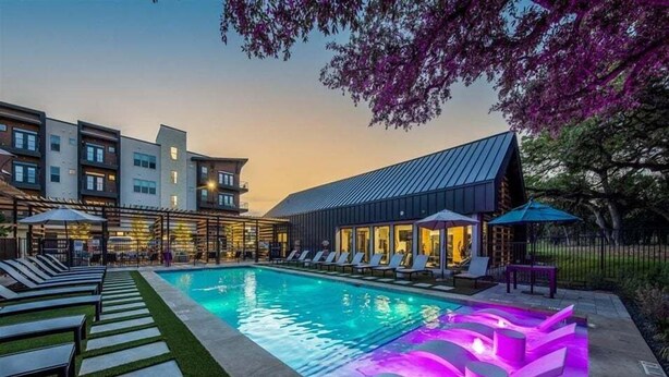 A swimming pool with lounge chairs and a covered seating area, surrounded by buildings with a modern architectural style. - Spacious 1BR w/ Patio, Pool & Gym Access (Austin)