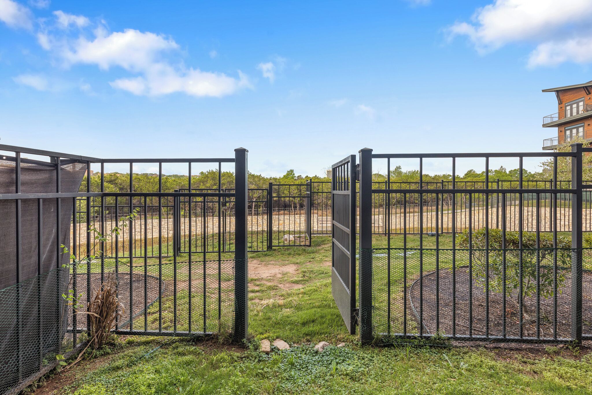 A gated area with a clear sky, a fenced enclosure, and a building in the background.