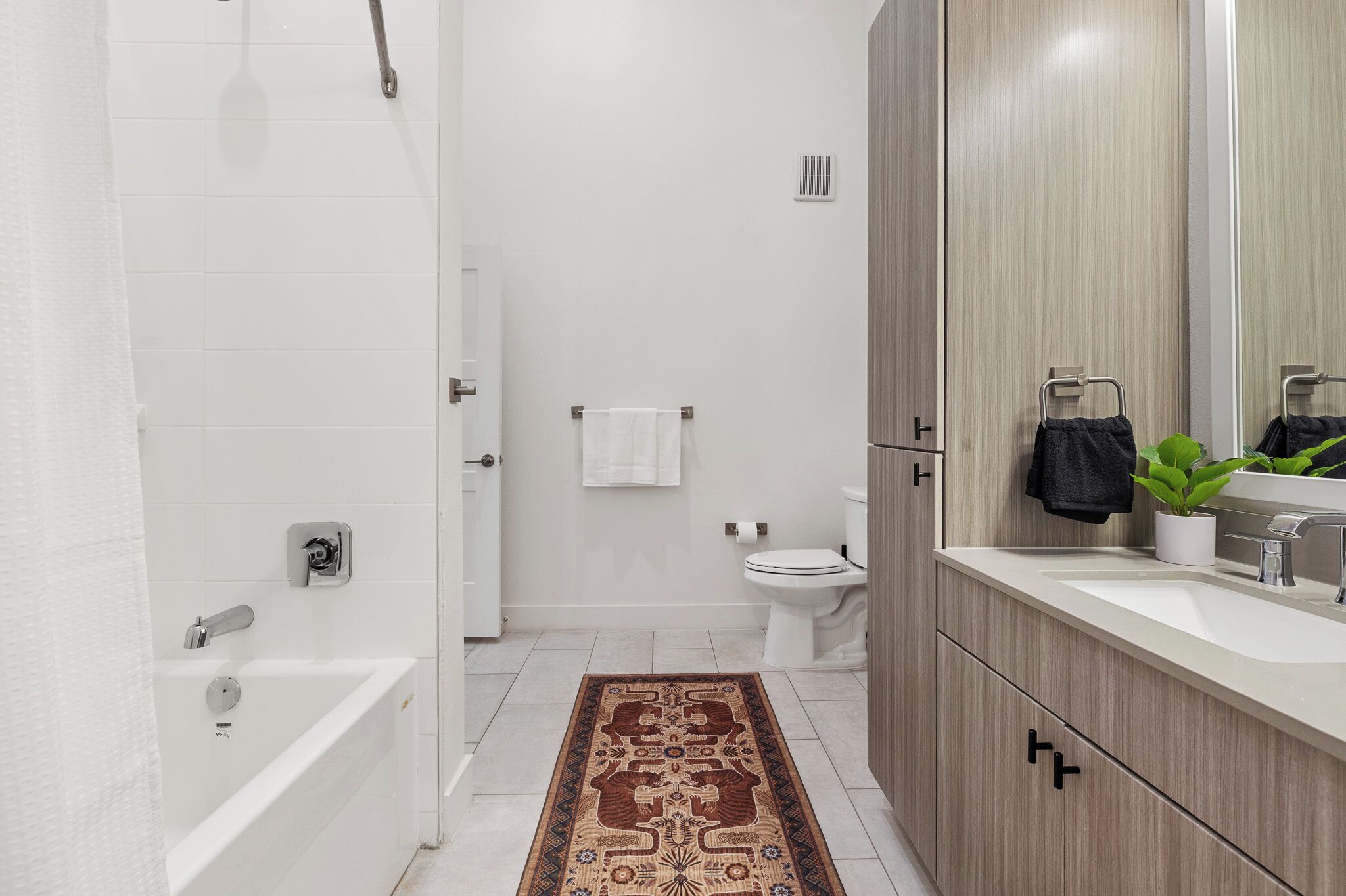 Een moderne badkamer met een bad, toilet en wastafel.