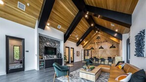 A spacious living area with a modern design, featuring a wooden ceiling, a fireplace, and a seating area with a sofa and chairs. - Spacious 1BR w/ Patio, Pool & Gym Access (Austin)