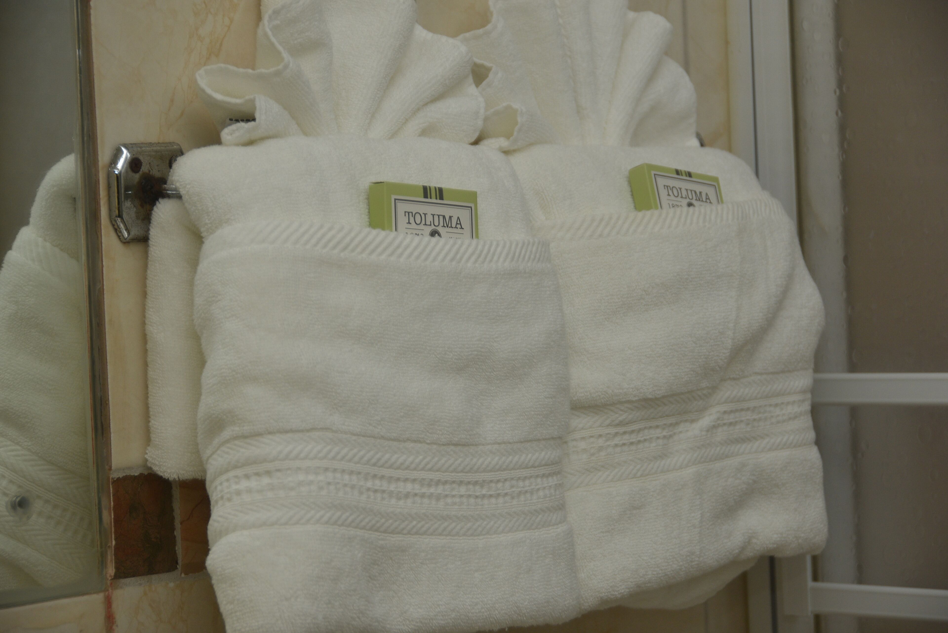A white towel with a 'TOLUMA' tag hanging on a bathroom door.