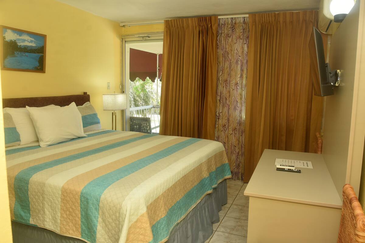 Una habitación de hotel con una cama, un escritorio, una lámpara y un cuadro en la pared.