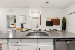 Una cucina moderna con lavello in acciaio inossidabile, mobili bianchi e lavastoviglie integrata.
