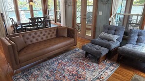 Una sala de estar acogedora con un sofá de cuero marrón, sillones tapizados en gris y un suelo con estampado.