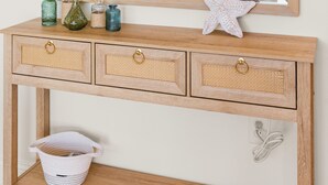 Een houten console tafel met drie lades, een spiegel en decoratieve items, waaronder een zeester.