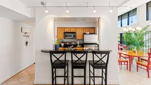 Een moderne keuken met een centraal eiland, barkrukken en een eethoek met rode stoelen.