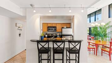 A modern kitchen with a central island, bar stools, and a dining area with red chairs.