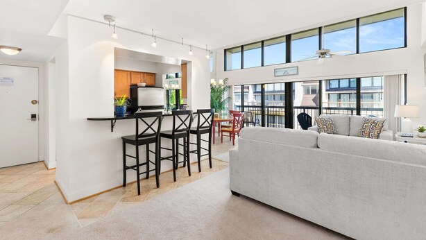 Een modern interieur met een keuken, eethoek en zithoek, met een hoge plafond en grote ramen.