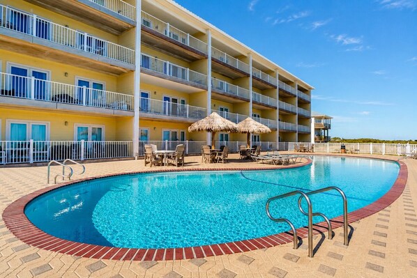 Um hotel com piscina, área de estar externa e um edifício com vários andares.