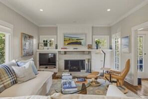 Ein Wohnzimmer mit Kamin, Sofa, Fernseher und Büchern.