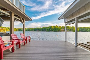 A wooden deck with red chairs and a view of a lake. - Lakefront, Dock, Slide, Tiki Bar, Kayaks, Fire pit, Pet Friendly (Bracey)
