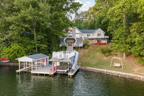 A lakeside property with a dock, a covered area, and a house with a large deck. - Lakefront, Dock, Slide, Tiki Bar, Kayaks, Fire pit, Pet Friendly (Bracey)