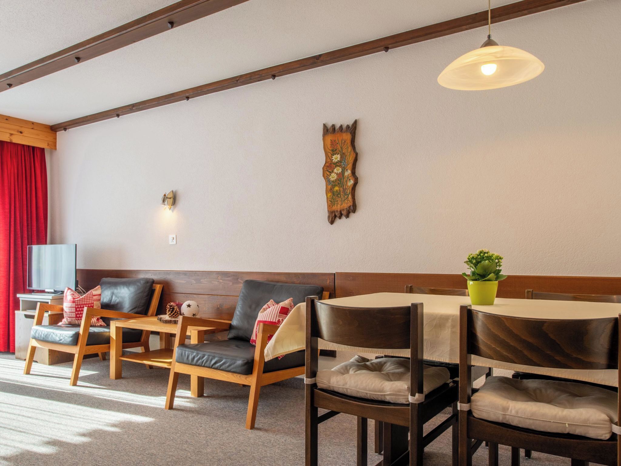 Une pièce chaleureuse avec un plafond en bois, une table à manger avec des chaises, un canapé et un téléviseur.