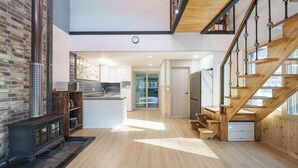 Eine geräumige Küche mit Holztreppe, Ziegelwand und einer modernen Kücheninsel.