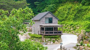 Ein Haus mit einem großen Balkon, umgeben von Felsen und viel Grün.