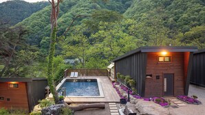 Ein modernes Resort mit Pool, Holzhütten und einer Bergkulisse.