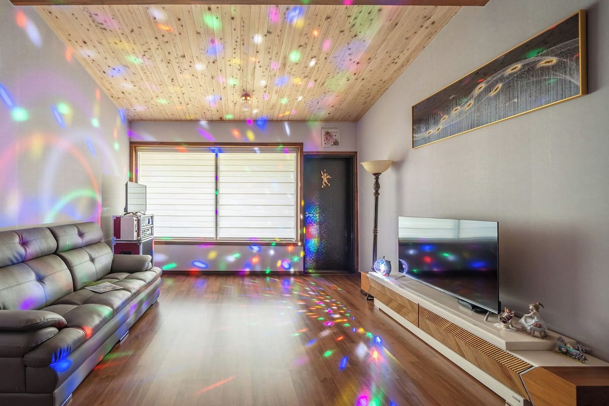Una sala de estar con un sofá, un televisor y techo de madera.