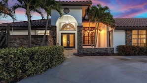 A two-story house with a stone facade, a large arched entrance, and a well-lit front porch.