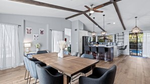 A modern kitchen with a central island, pendant lighting, and a view to the outside.